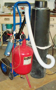 Portable sandblaster setup with wheels and dust collector.
