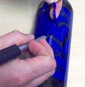Sandblasting stencil being applied to a glass bottle.