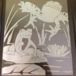 Frog designs etched on glass surface.