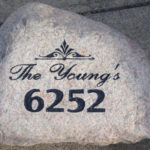 Sandblasting large landscaping rock with address.