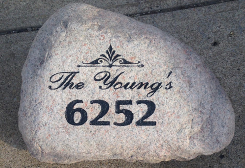 Sandblasting large landscaping rock with address.