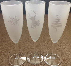 A Christmas tree, reindeer and snowflake reverse (negative) etched on Champagne glasses.